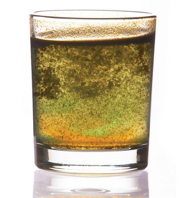 toxic water in glass with turbid sediment, yellow and green color. isolated on the white background